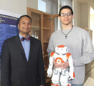 Marquette-University-Professor-Andrew-Williams-engineering-student-Jerrell-Jones-holding-robot-used-in-engineering-research-lab