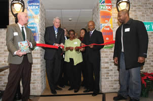 Gary White of PyraMax Bank (left) and Immanuel Mills of Focus on Energy (right) and other dignitaries watch as Mayor Tom Barrett, Lapham Park Resident Organization President Catherine Vance and Common Council President and Housing Authority Chair Willie L. Hines, Jr. cut a ribbon to celebrate the grand re-opening of Lapham Park.